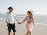 Paar spaziert lachend am Meer | Verlobungsringe