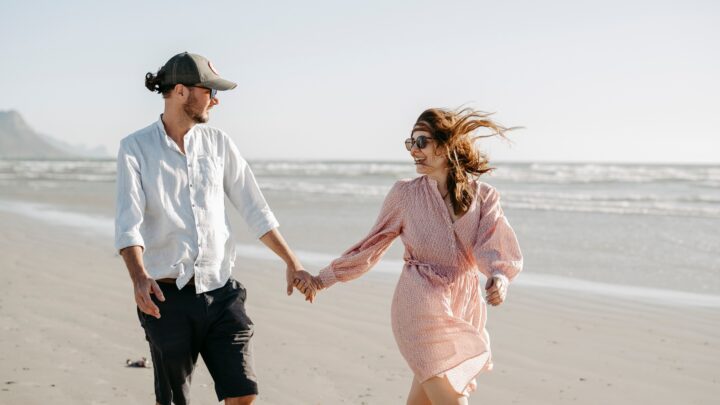 Paar spaziert lachend am Meer | Verlobungsringe